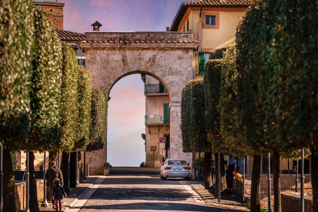 aged stone arch and residential buildings in old town at sundown